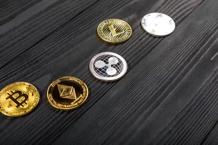 Silver and golden coins with bitcoin, ripple and ethereum symbol on wood background.