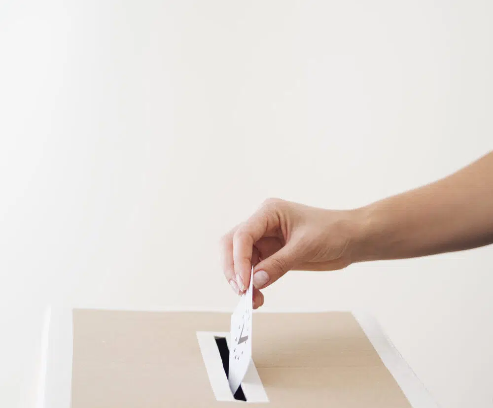a side view of a person putting a ballot in a box